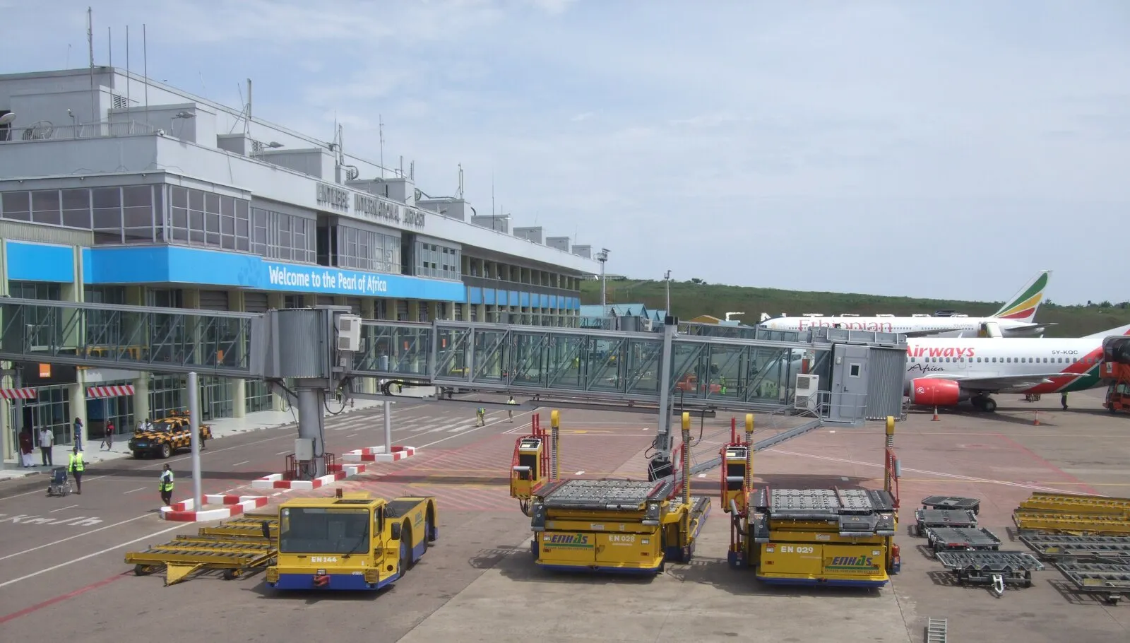 The terminal building at Entebbe International Airport, with a jet bridge extended to an Ethiopian Airlines aircraft and a Kenya Airways plane parked at an adjacent gate